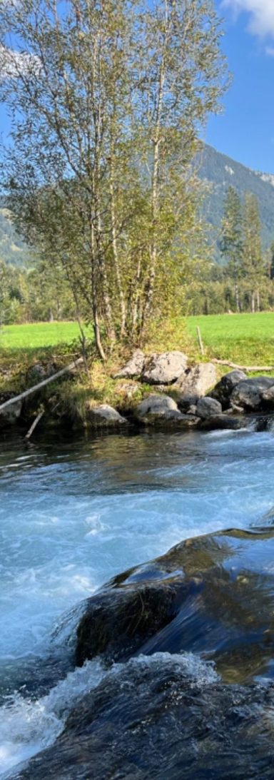 Flusslandschaft mit klarem Wasser und Bergen im Hintergrund – Symbol für Balance, innere Ruhe und natürliche Bewegung im Go Beyond Retreat